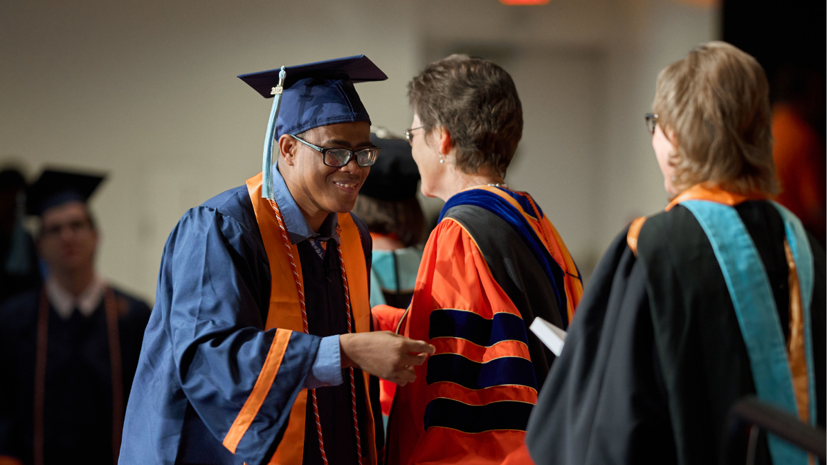 InclusiveU student walking across the stage at graduation.